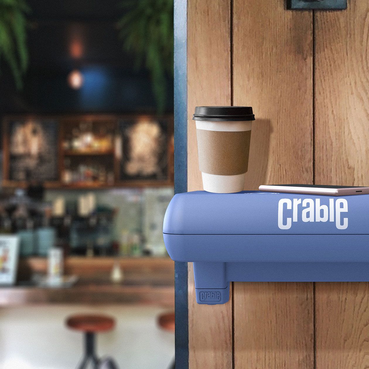 Crable shelf in cafe wirelessly charging a mobile phone with cup of coffee placed on